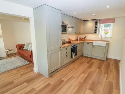 a kitchen with white cabinets and a wooden floor at Cobble Cottage in Keswick