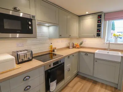 a kitchen with white cabinets and a sink and a microwave at Cobble Cottage in Keswick