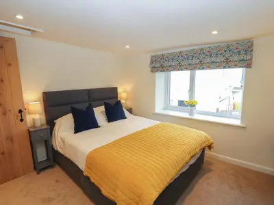 a bedroom with a bed with a yellow blanket and a window at Cobble Cottage in Keswick