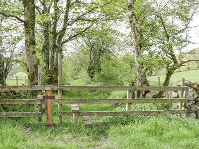 a wooden fence in front of a field with trees at Cobble Cottage in Keswick