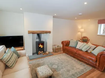 a living room with a leather couch and a fireplace at Cobble Cottage in Keswick