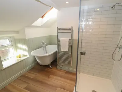 a bathroom with a bath tub and a sink at Cobble Cottage in Keswick
