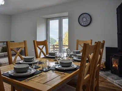 a dining room with a wooden table and a fireplace at Striding Edge Cottage in Glenridding