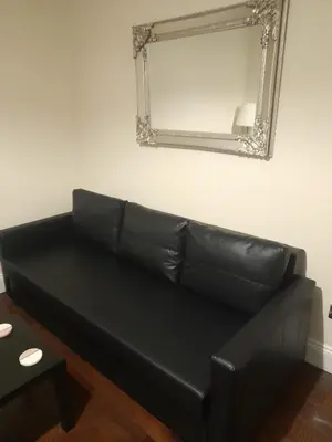 a black leather couch in a living room with a mirror at Kirkcudbright Holiday Apartments - Apartment D in Kirkcudbright