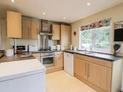 a kitchen with wooden cabinets and white appliances at Eden Lodge in Newton Stewart