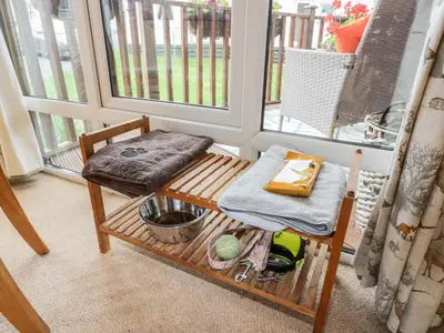 a porch with a bench and a table and a window at Eden Lodge in Newton Stewart
