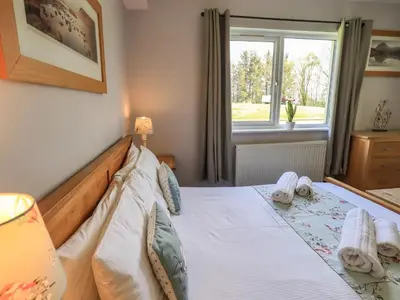 a bedroom with a large bed with a window at Mallard Cottage Lake District, Leisure Spa Pool & Gym in Penruddock