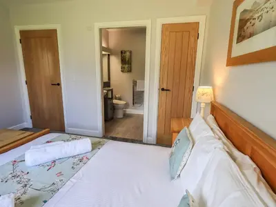 a bedroom with a bed and a bathroom at Mallard Cottage Lake District, Leisure Spa Pool & Gym in Penruddock