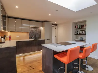 a kitchen with an island with orange bar stools at Hardhills Cottage in Castle Douglas