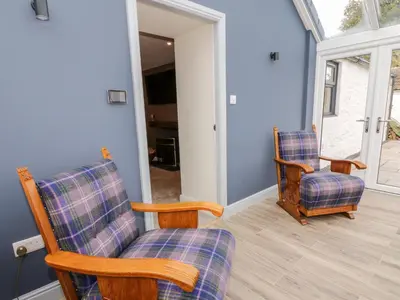 two chairs in a living room with blue walls at Hardhills Cottage in Castle Douglas
