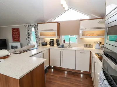 a kitchen with white cabinets and a large window at No 7 Skiddaw View in Cockermouth