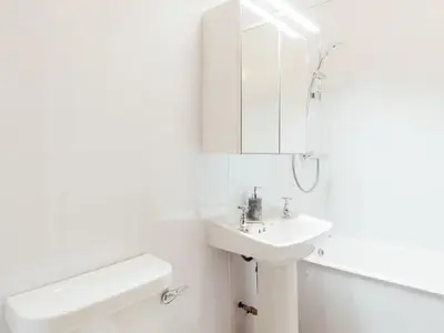 a white bathroom with a sink and a mirror at Middle Byre at Clauchan Holiday Cottages in Gatehouse of Fleet