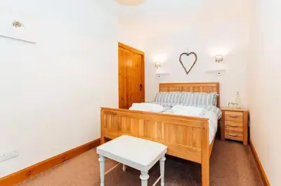 a bedroom with a wooden bed and a bench at Middle Byre at Clauchan Holiday Cottages in Gatehouse of Fleet