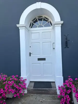 a white door with an arched window and purple flowers at Penthouse apartment in Cockermouth