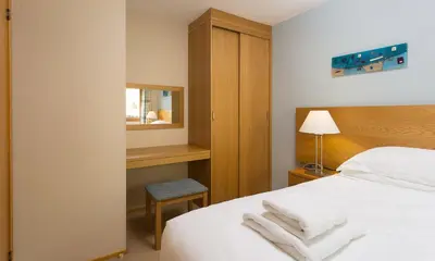a bedroom with a bed and a chair and a mirror at Keswick Bridge Lodge Resort in Keswick