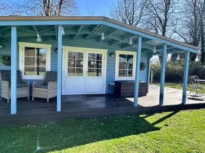 a blue house with a porch and chairs on a deck at Oak View Lodge: Cosy, Countryside Retreat in Maybole