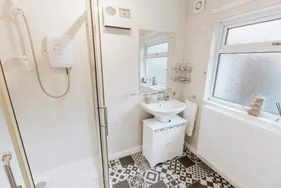 a white bathroom with a sink and a shower at Winnie's Cottage - 3 Bed Accommodation in Cumbria in Mealsgate