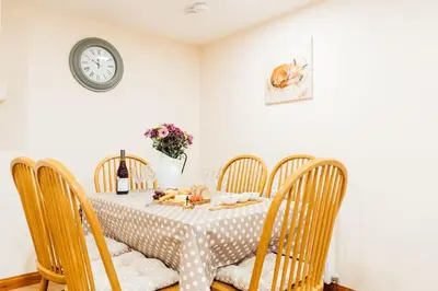 a dining room with a table and chairs with a clock at The Barn @ Clauchan holiday Cottages in Gatehouse of Fleet
