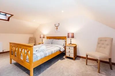 a bedroom with a wooden bed and a chair at The Barn @ Clauchan holiday Cottages in Gatehouse of Fleet