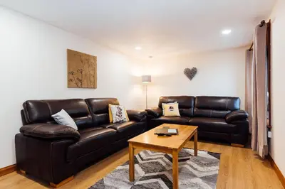 a living room with a leather couch and a table at The Barn @ Clauchan holiday Cottages in Gatehouse of Fleet