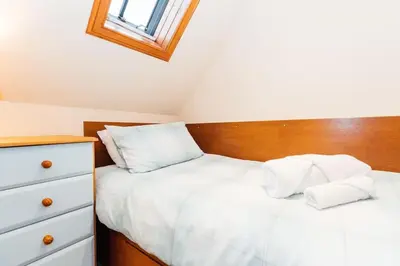 a bedroom with two beds with white sheets and a wooden headboard at The Stable at Clauchan Holiday Cottages in Gatehouse of Fleet