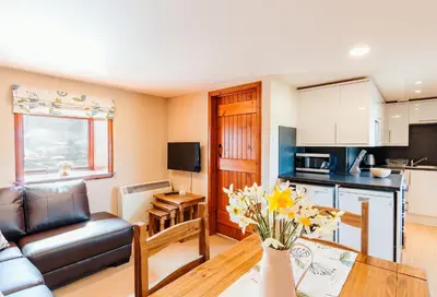 a kitchen and living room with a couch and a table at The Stable at Clauchan Holiday Cottages in Gatehouse of Fleet