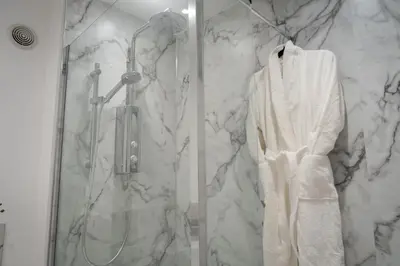 a bathroom with a shower with a white robe at Bridge View in Annan
