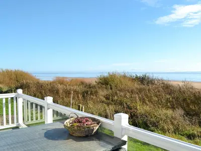 a basket of flowers sitting on a porch with the beach at Gill Bay - Uk45513 in Mainsriddle