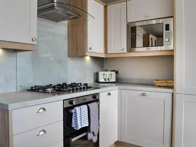 a white kitchen with a stove and a microwave at Gill Bay - Uk45513 in Mainsriddle