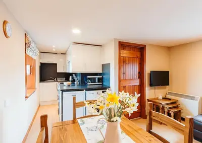 a kitchen and dining room with a vase of flowers on a table at Valley View at Clauchan Holiday Cottages in Gatehouse of Fleet