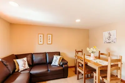 a living room with a leather couch and a table at Valley View at Clauchan Holiday Cottages in Gatehouse of Fleet