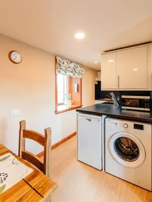 a kitchen with a washing machine and a table at Valley View at Clauchan Holiday Cottages in Gatehouse of Fleet