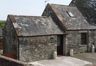 an old stone building with a door at The Dairy Bothy at Clauchan Holiday Cottages in Gatehouse of Fleet