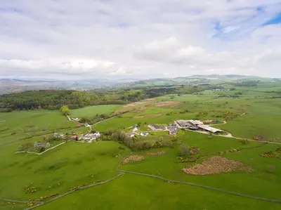 an aerial view of a house in a green field at The Dairy Bothy at Clauchan Holiday Cottages in Gatehouse of Fleet