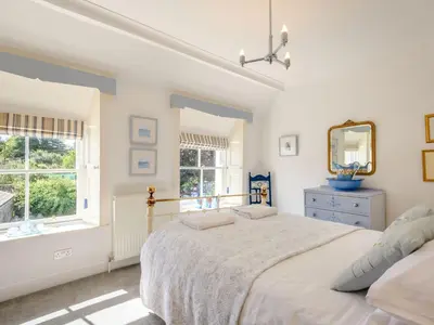 a white bedroom with a bed and a mirror at Priory Walk in Newton Stewart