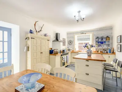 a kitchen with white cabinets and a wooden table at Priory Walk in Newton Stewart