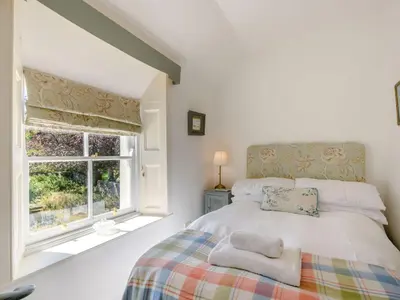 a white bedroom with a bed and a window at Priory Walk in Newton Stewart