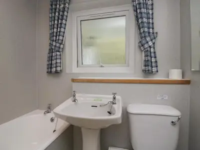 a bathroom with a sink and a toilet and a window at Apartment 4 in Keswick