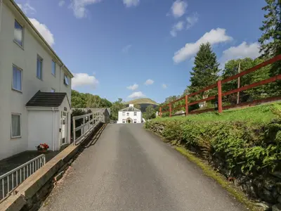 a road leading to a white house with a fence at Apartment 6 in Keswick