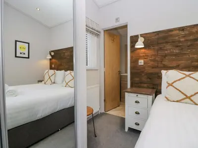 a bedroom with two beds and a mirror at The Bothy in Keswick