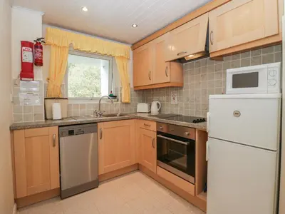 a kitchen with wooden cabinets and a white refrigerator at Apartment 2 in Keswick