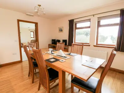 a dining room with a wooden table and chairs at Cairnhapple House in Stranraer