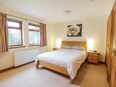 a bedroom with a large bed and two windows at Cairnhapple House in Stranraer