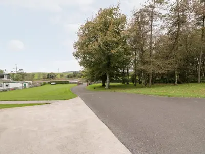a winding road with trees and a grass field at Cairnhapple House in Stranraer