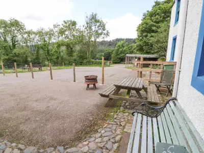 a park with two benches and a fire pit at Kestrel Cottage in Keswick