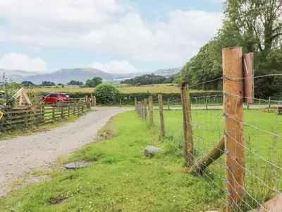 a fence on a dirt road next to a field at Kestrel Cottage in Keswick