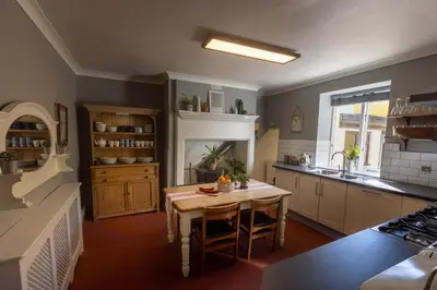 a kitchen with a table and a fireplace in it at CastlegateTownhouse in Cockermouth