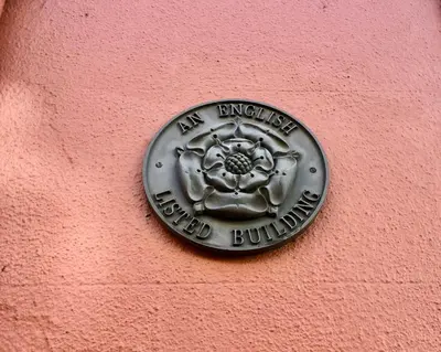 a metal plaque on a pink wall with a building at CastlegateTownhouse in Cockermouth