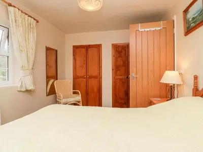 a bedroom with a bed and a chair and a window at Thwaite How in Keswick