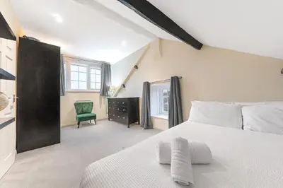 a bedroom with a white bed and a green chair at Town centre property convenient for the fells in Keswick